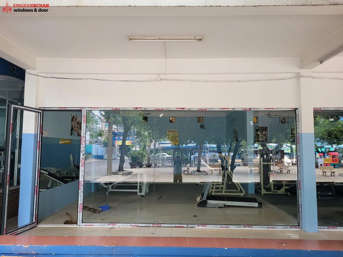 Lắp đặt cửa nhôm Xingfa mở quay 1 cánh và vách kính cố định tại phòng gym trường Thanh Bình